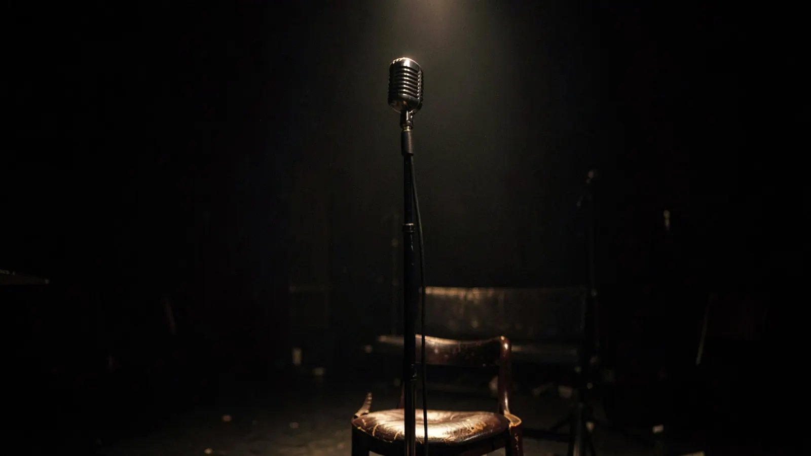 Spotlit microphone and stool on a dimly lit jazz club stage.