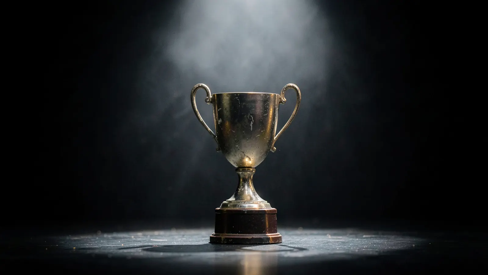 Trophy on an empty stage under a spotlight, with a faint haze.
